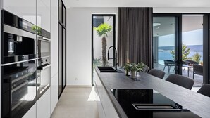 A modern kitchen with built-in appliances and a long dining table with chairs.
