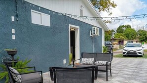 A patio with two wicker chairs and a table, a blue house, and a parked car. - Perfect Location! All include Tampa Private Suite (Tampa)