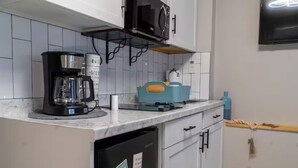 A kitchen with white cabinets, a black coffee maker, a teal storage basket, and a microwave. - Perfect Location! All include Tampa Private Suite (Tampa)