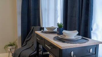 A modern kitchen with a dark countertop, a wooden chair, and a potted plant.
