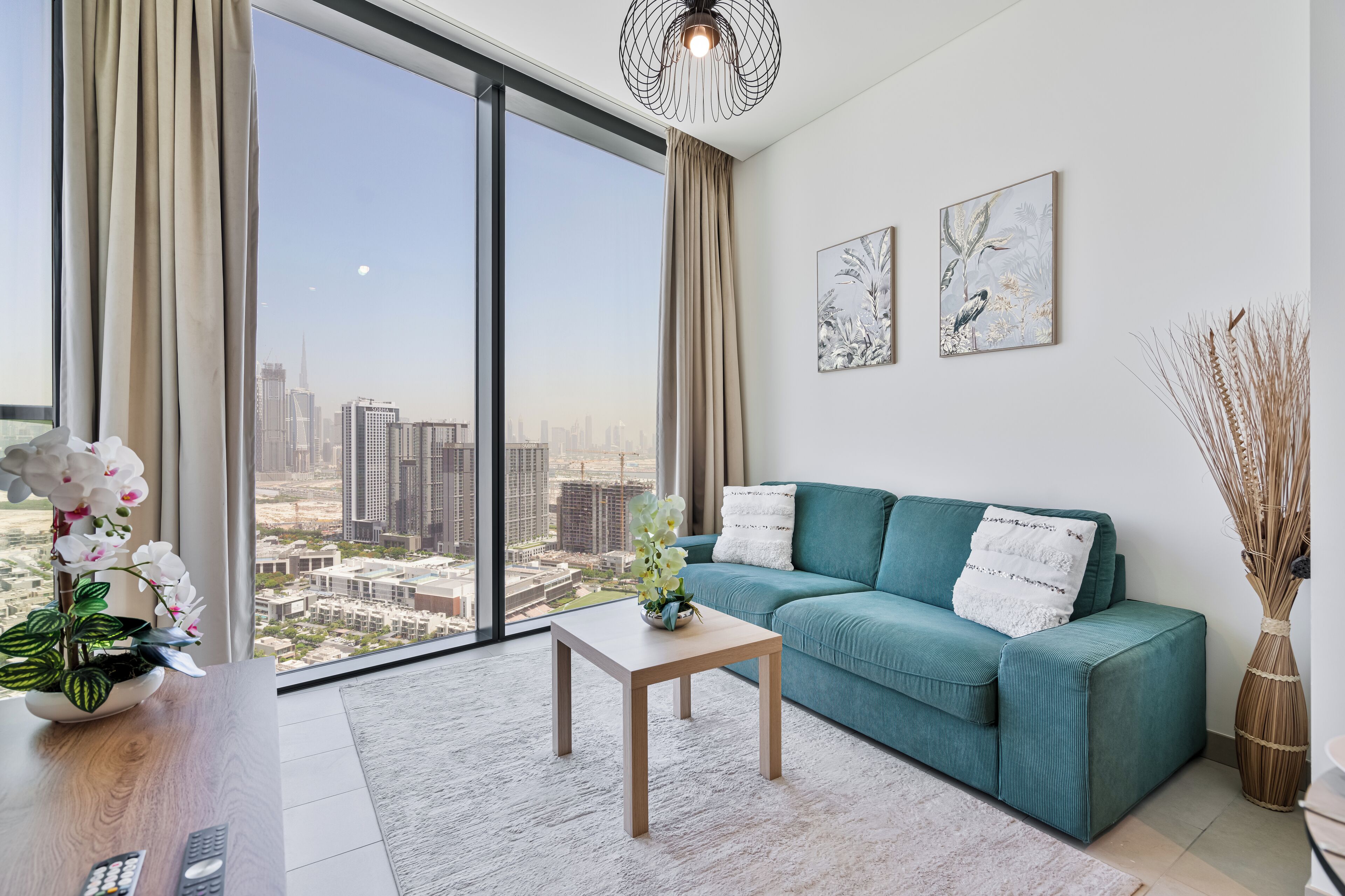 Un salon moderne avec un canapé de couleur turquoise, une table basse en bois et une vue sur la ville à travers de grandes fenêtres.