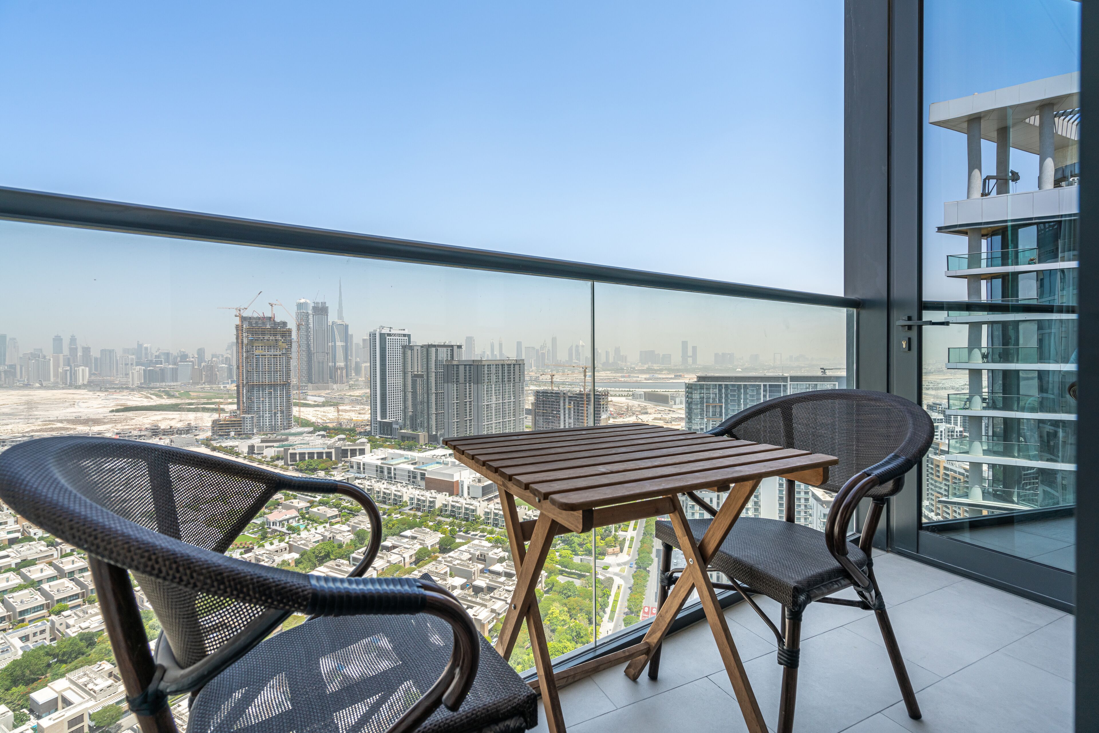 Varanda com mesa e cadeiras, com vista para a cidade.
