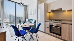 Une cuisine moderne avec une grande fenêtre, un coin repas avec des chaises bleues et une vue sur la ville.