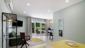 Ein Hotelzimmer mit Bett, Schreibtisch, Stuhl, Fernseher und einer Schiebetür zum Balkon.