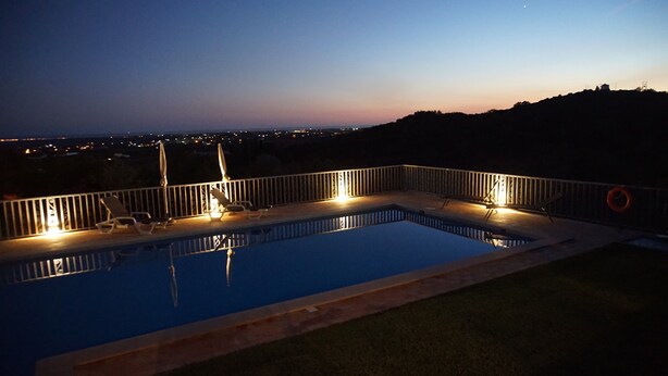 Ein Schwimmbad mit Blick auf die Stadt im Abendrot.
