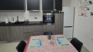 Et moderne køkken med spiseplads, med et bord dækket til to med et rødt og hvidt ternet dug.