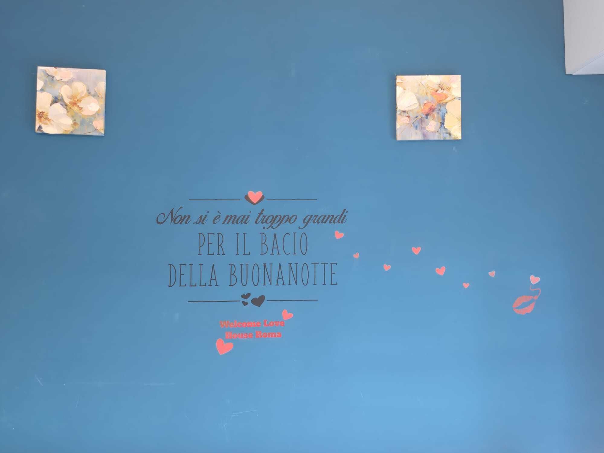 A blue wall with a decorative message in Italian, surrounded by small heart shapes.