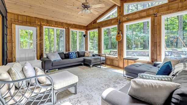 Une pièce spacieuse avec un grand canapé d’angle, une petite table et un ventilateur de plafond.