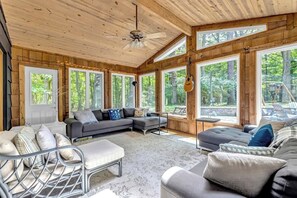 A spacious room with a large sectional sofa, a small table, and a ceiling fan.