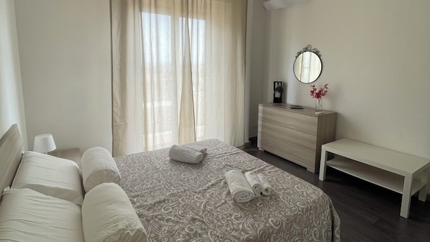 A bedroom with a bed, a bedside table, a mirror, a dresser, and a ceiling fan. - Cibali Metro Stay (Catania)
