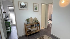 A hallway with a wooden console table, framed pictures, a rug, and a hanging light fixture. - Cibali Metro Stay (Catania)