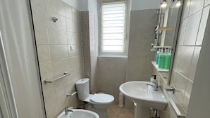 A compact bathroom with a toilet, bidet, sink, and a small window. - Cibali Metro Stay (Catania)