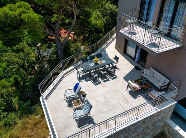A rooftop terrace with a dining area, seating, and a small balcony.