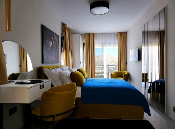 A hotel room with a bed, a desk, a chair, a TV, and a window with curtains.