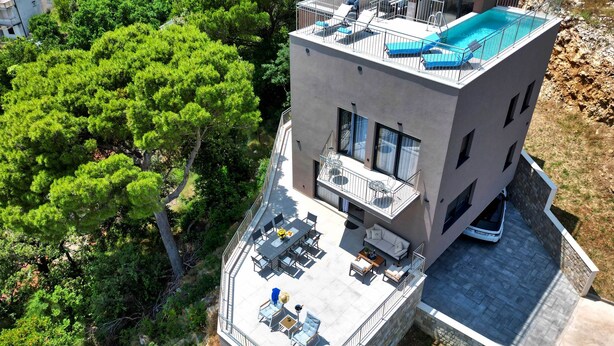 Un edificio moderno de dos pisos con piscina en la azotea, un espacio de estar techado al aire libre y vistas a zonas verdes.