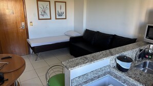 A compact room with a bed, a sofa, a small kitchen area with a sink, and a television. - Golden Dolphin Grand Hotel (Caldas Novas)