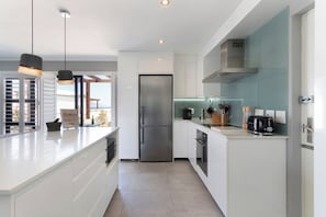A modern kitchen with a central island, stainless steel appliances, and pendant lighting.