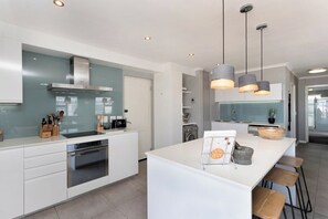A modern kitchen with a central island, stainless steel appliances, and pendant lighting.