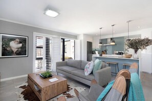 A modern living room with a sofa, coffee table, and a view of the kitchen.
