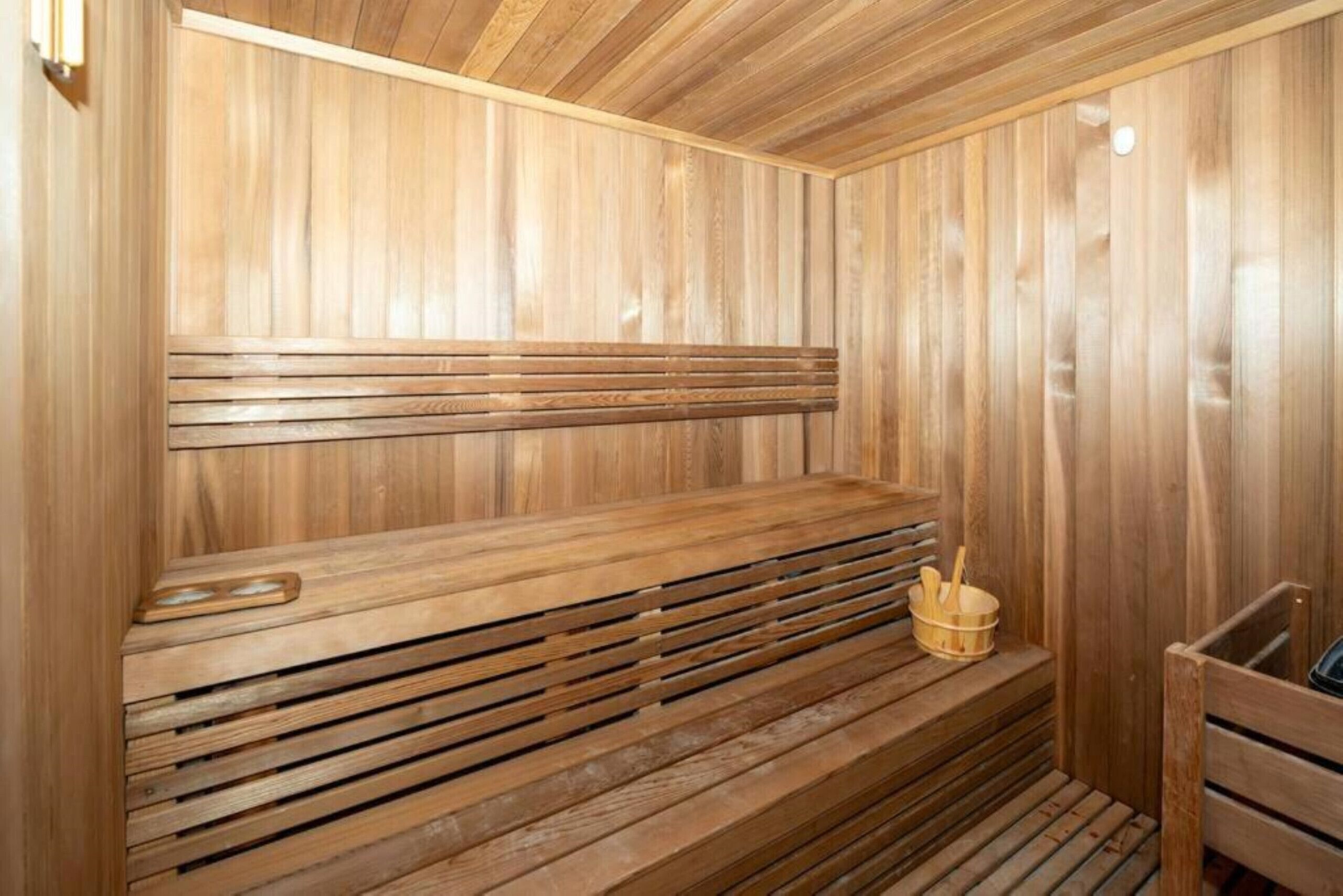 Eine Holzsauna mit Bänken und einer kleinen Holzschüssel.