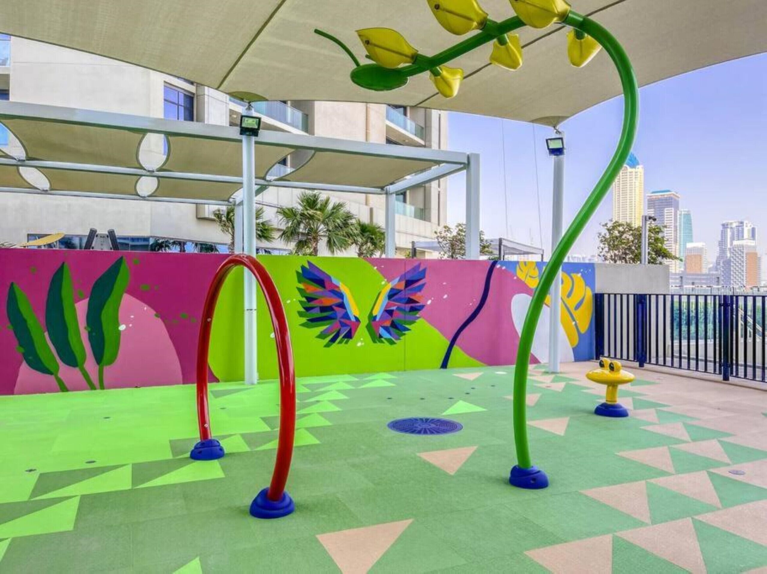 Ein Spielbereich im Freien mit farbenfrohen Wandgemälden und geometrischen Mustern auf dem Boden.