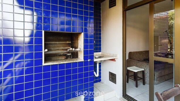 Uma cozinha com azulejos azuis, forno embutido e um banquinho pequeno.