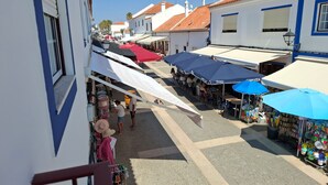 Une rue étroite bordée de boutiques et de terrasses, avec des toits en tuiles et des bâtiments blancs aux ornements bleus.