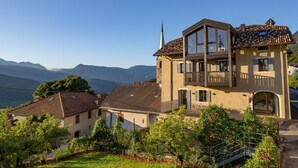 Un bâtiment à deux étages doté d’un balcon, d’une tour horlogère et offrant une vue sur les montagnes.