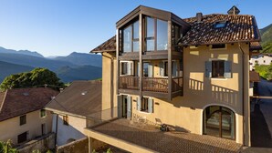 Un immeuble à plusieurs étages doté de balcons, de grandes fenêtres et offrant une vue sur les montagnes.