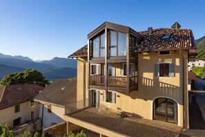 A multi-story building with balconies, large windows, and a view of mountains. - 734A Mendelglück Apartments (Caldaro sulla strada del vino)