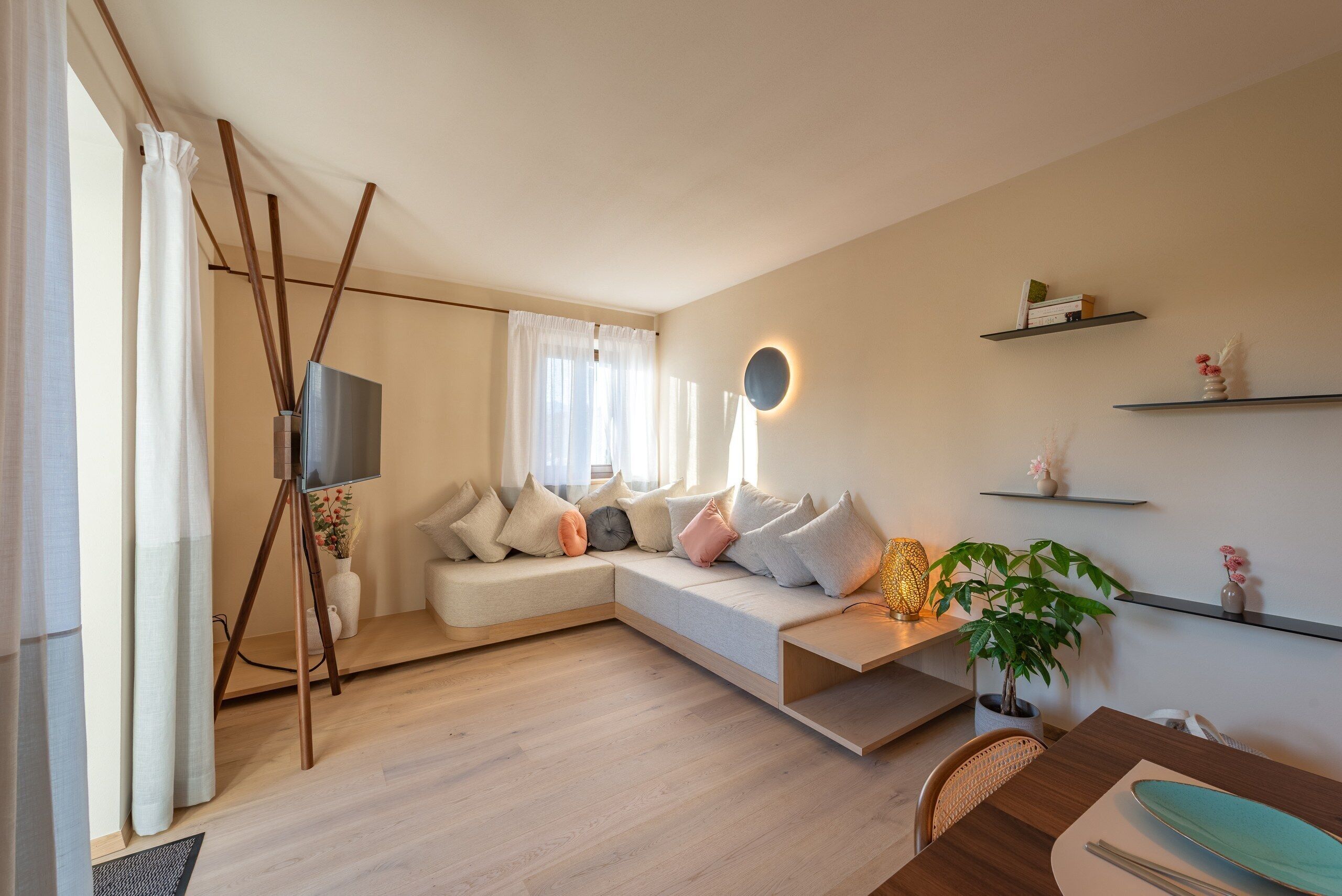 Un salon moderne avec un canapé d’angle, un téléviseur à écran plat et un coin repas comprenant une table et des chaises.