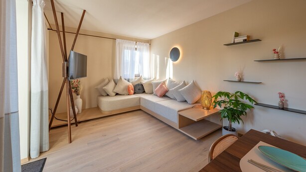 Un salon moderne avec un canapé d’angle, un téléviseur à écran plat et un coin repas comprenant une table et des chaises.