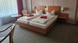 A hotel room with a large bed, two bedside tables, a chair, and a small round table.