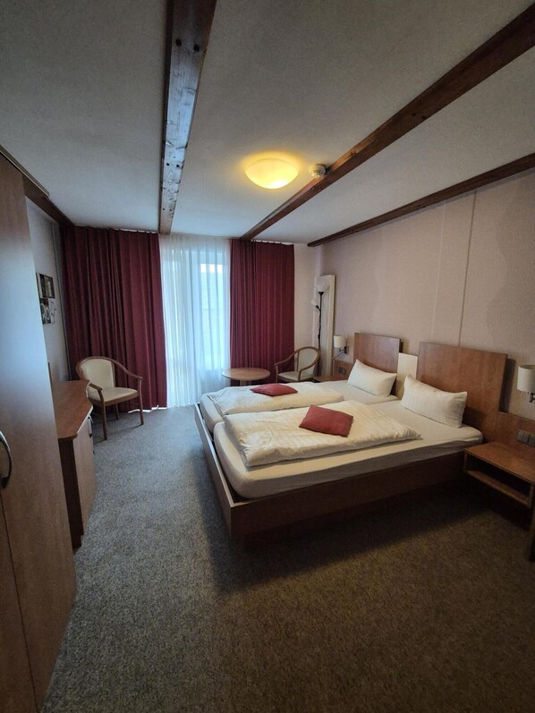 Una habitación de hotel con una cama grande, dos mesitas de noche, un escritorio y una silla.