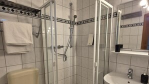 A bathroom with a glass-enclosed shower, a toilet, and a sink.
