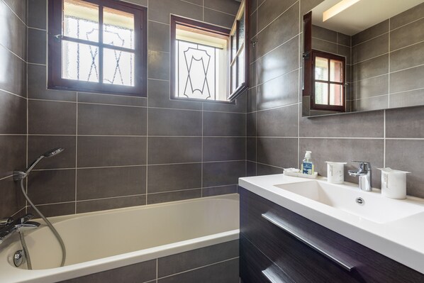 A modern bathroom with a bathtub, a sink, and a mirror. - Villa Delb – Mountain View, Private Pool, and Wi-Fi (Arthez-d'Asson)
