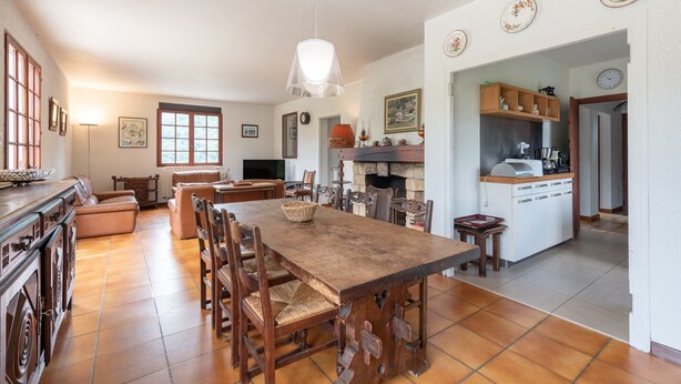 Una cocina amplia con una gran mesa de madera, sillas y una lámpara colgante.