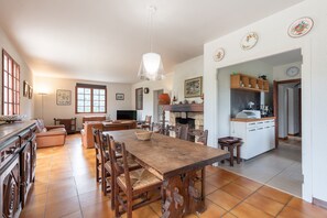 Een ruime keuken met een grote houten tafel, stoelen en een hanglamp.