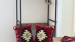 Eine Eckregaleinheit mit zwei gemusterten Kissen, einem kleinen Tisch und einem Stuhl.
