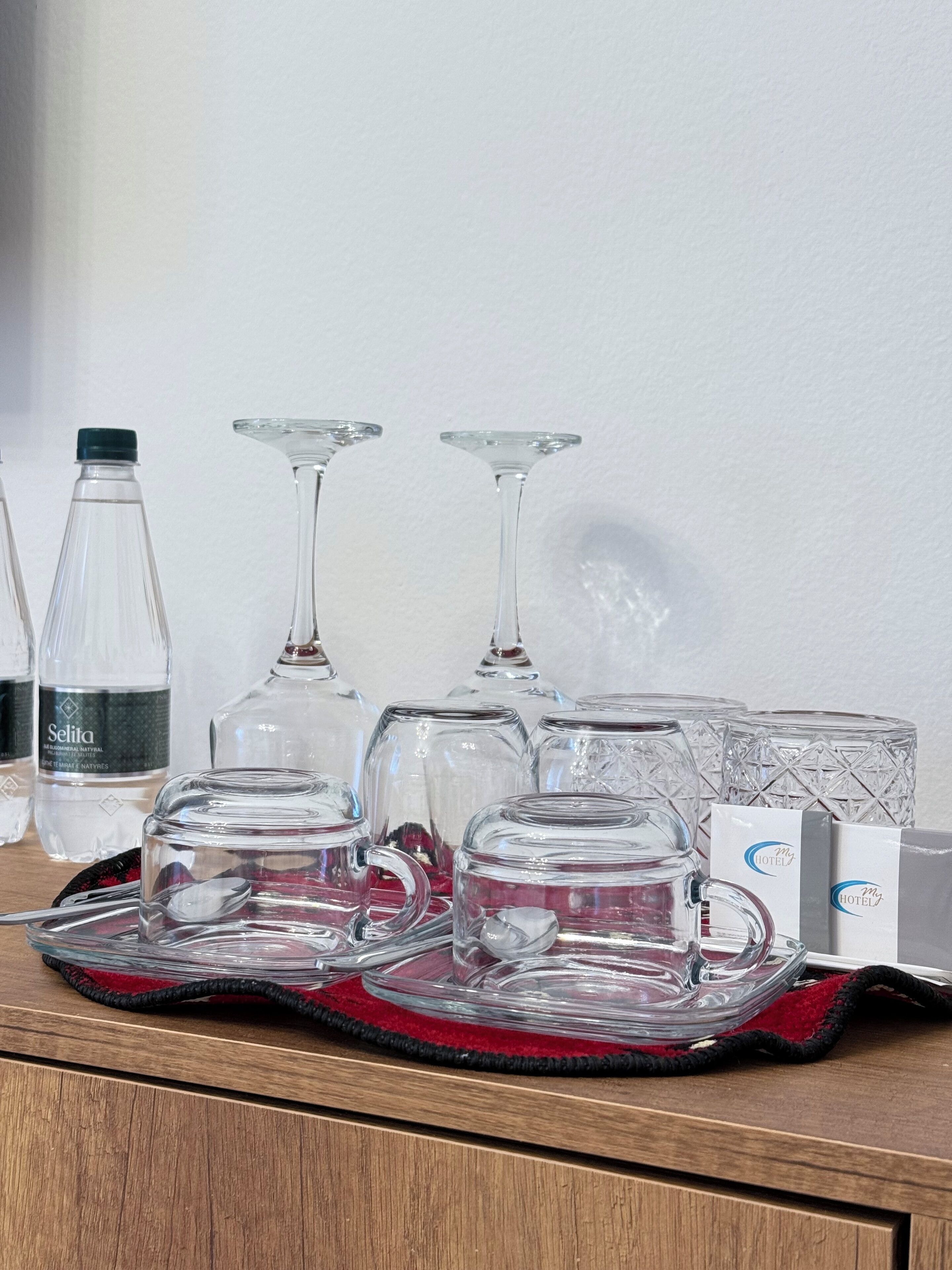 En bakke med glas og en flaske på en træoverflade.