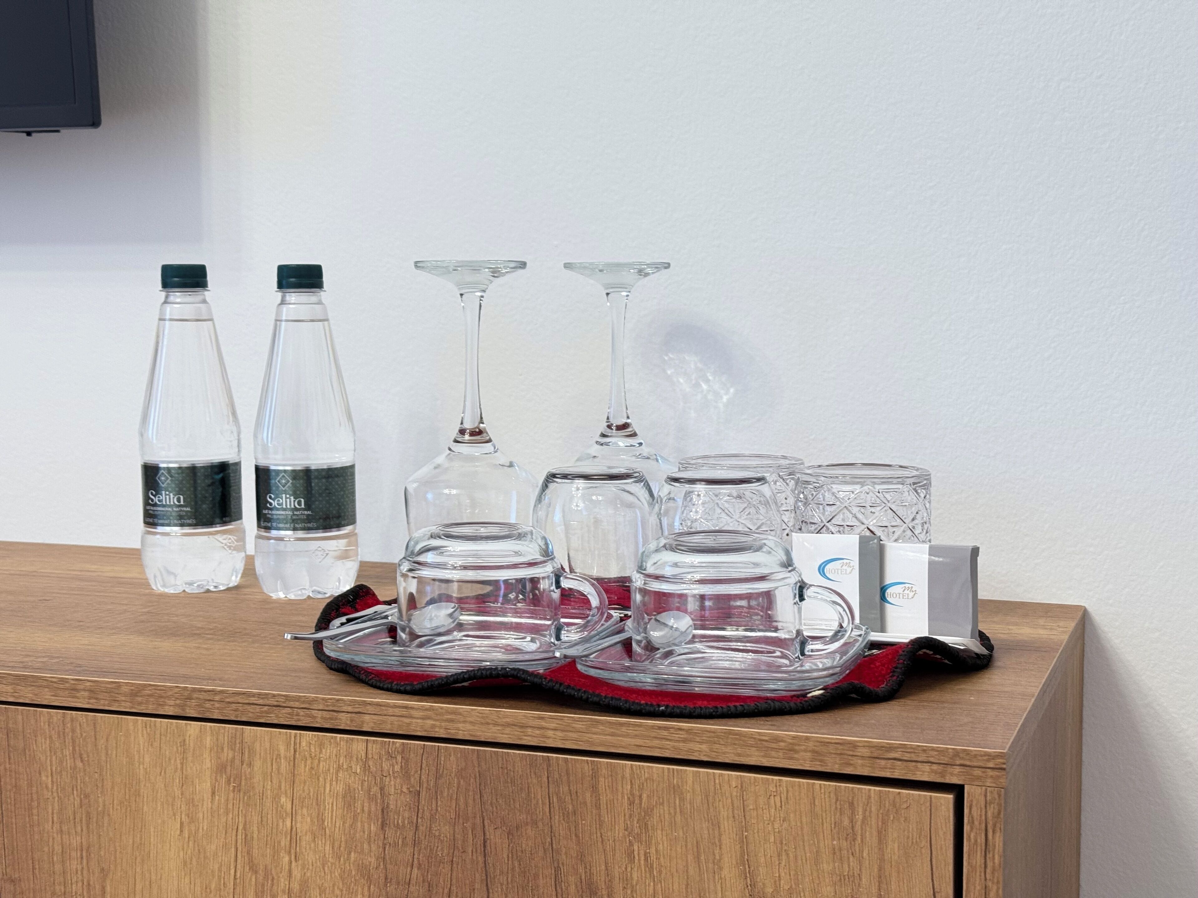 A minibar setup with bottles, glasses, and a tray.