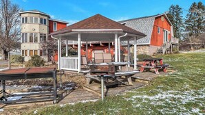 A gazebo with a wooden roof and white railings, surrounded by picnic tables and benches. - Red Barn Village Apartments (Clarks Summit)