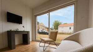 A modern room with a large window, a desk, a chair, and a sofa.