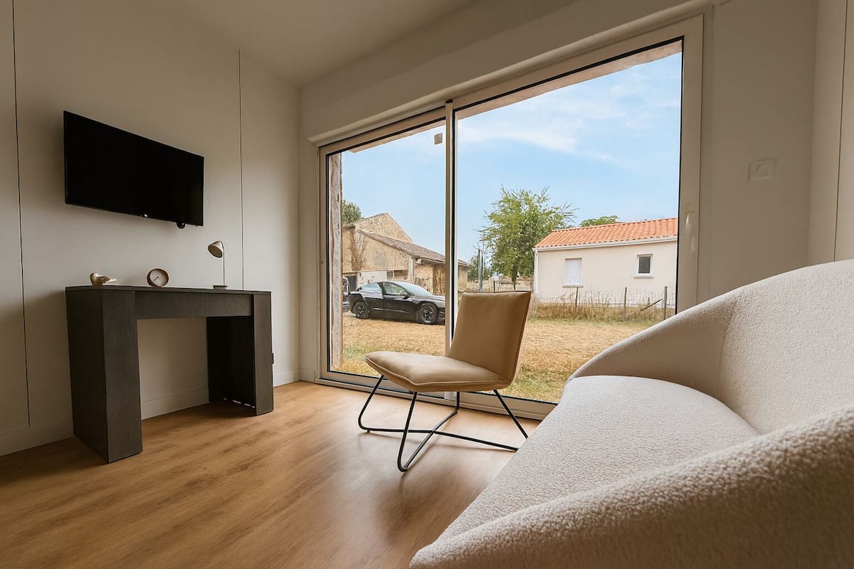 Een moderne kamer met een groot raam, een bureau, een stoel en een bank.