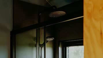 A glass-enclosed shower with a handheld showerhead and a window above it.