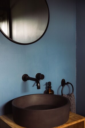 Un baño con un lavabo redondo, un espejo y un perchero para toallas.