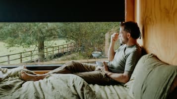 A person sitting on a bed with a window view of a natural landscape.