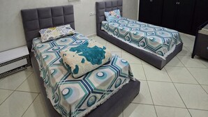A bedroom with two beds, a wardrobe, and a ceiling light fixture. - STANDING SAIDIA APARTMENT (Saïdia)