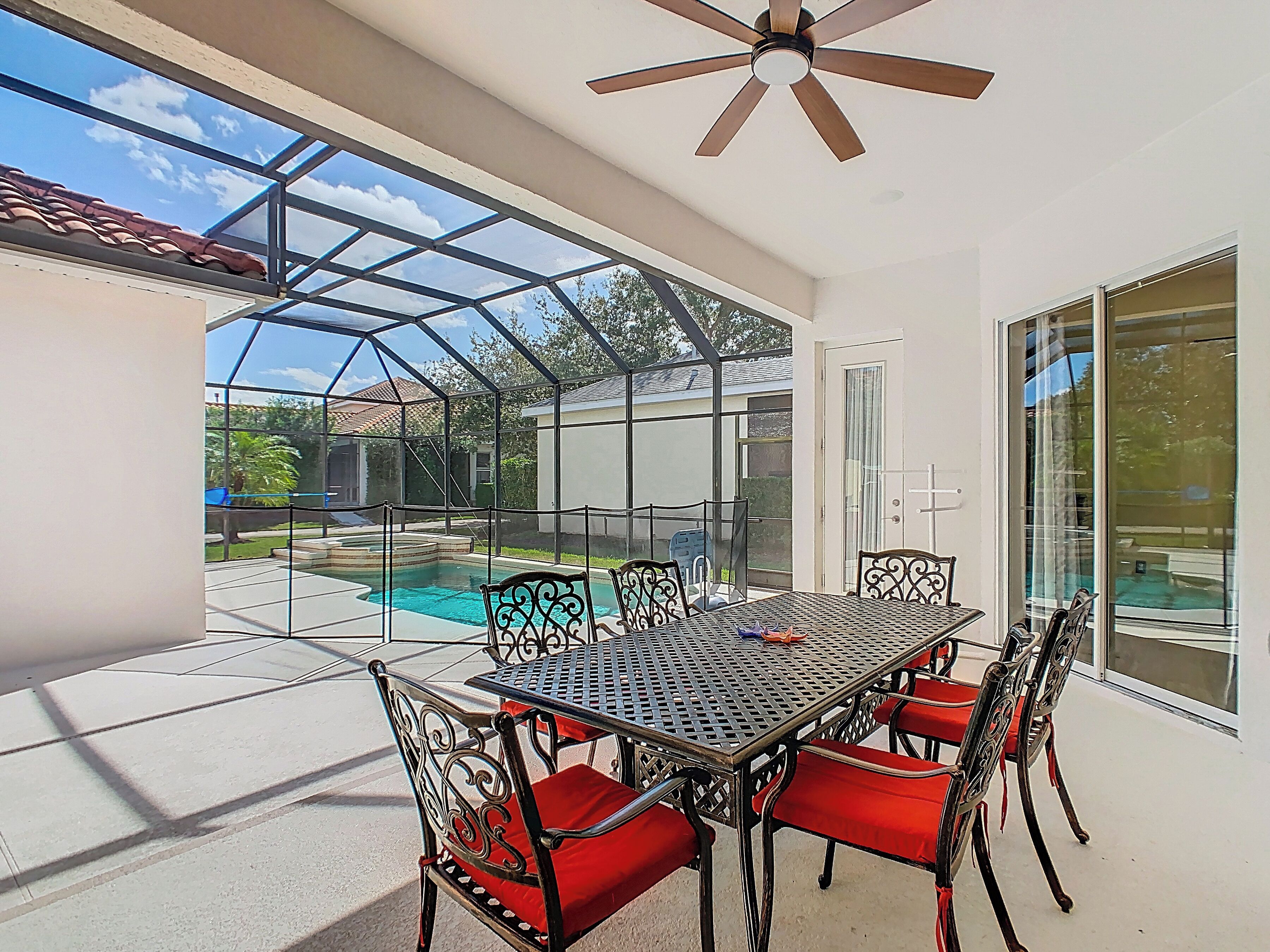 A covered patio with a pool, a table with chairs, and a ceiling fan.
