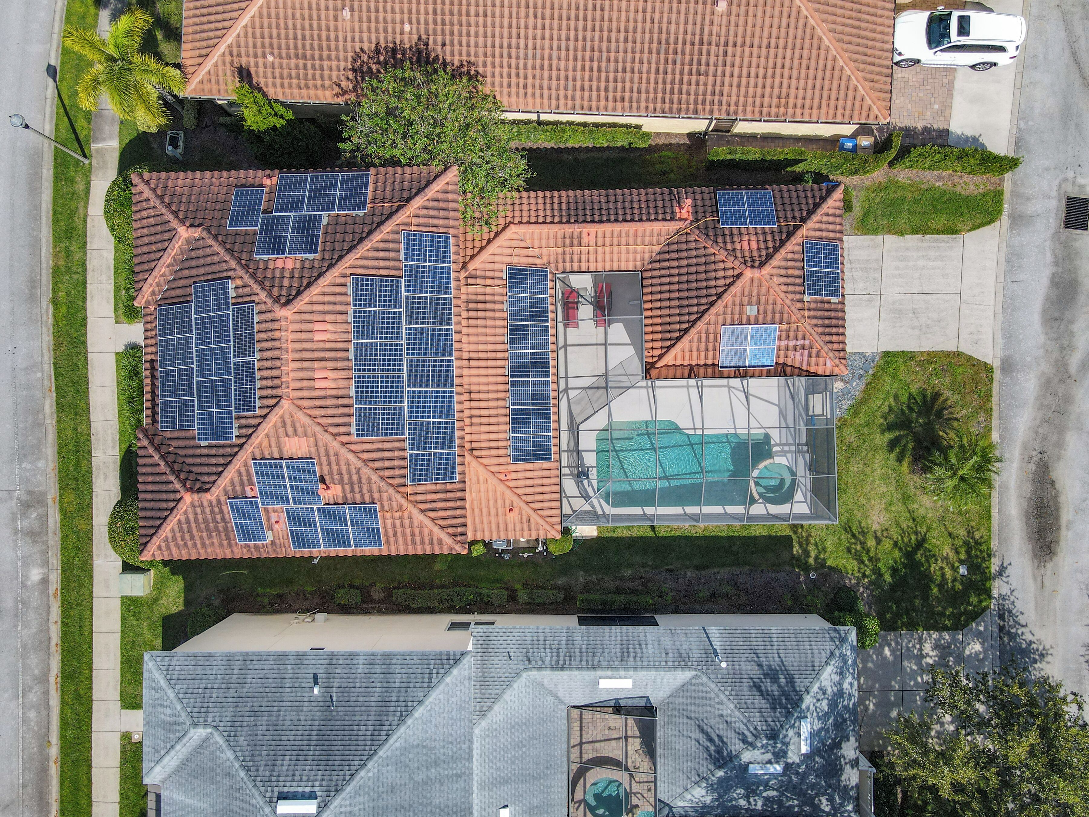 A residential area with multiple houses, each featuring solar panels on the roofs.